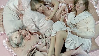 Vier junge Frauen in pastellfarbenen Kleidern liegen eng aneinander auf einem runden, gepolsterten Untergrund mit Rüschen.