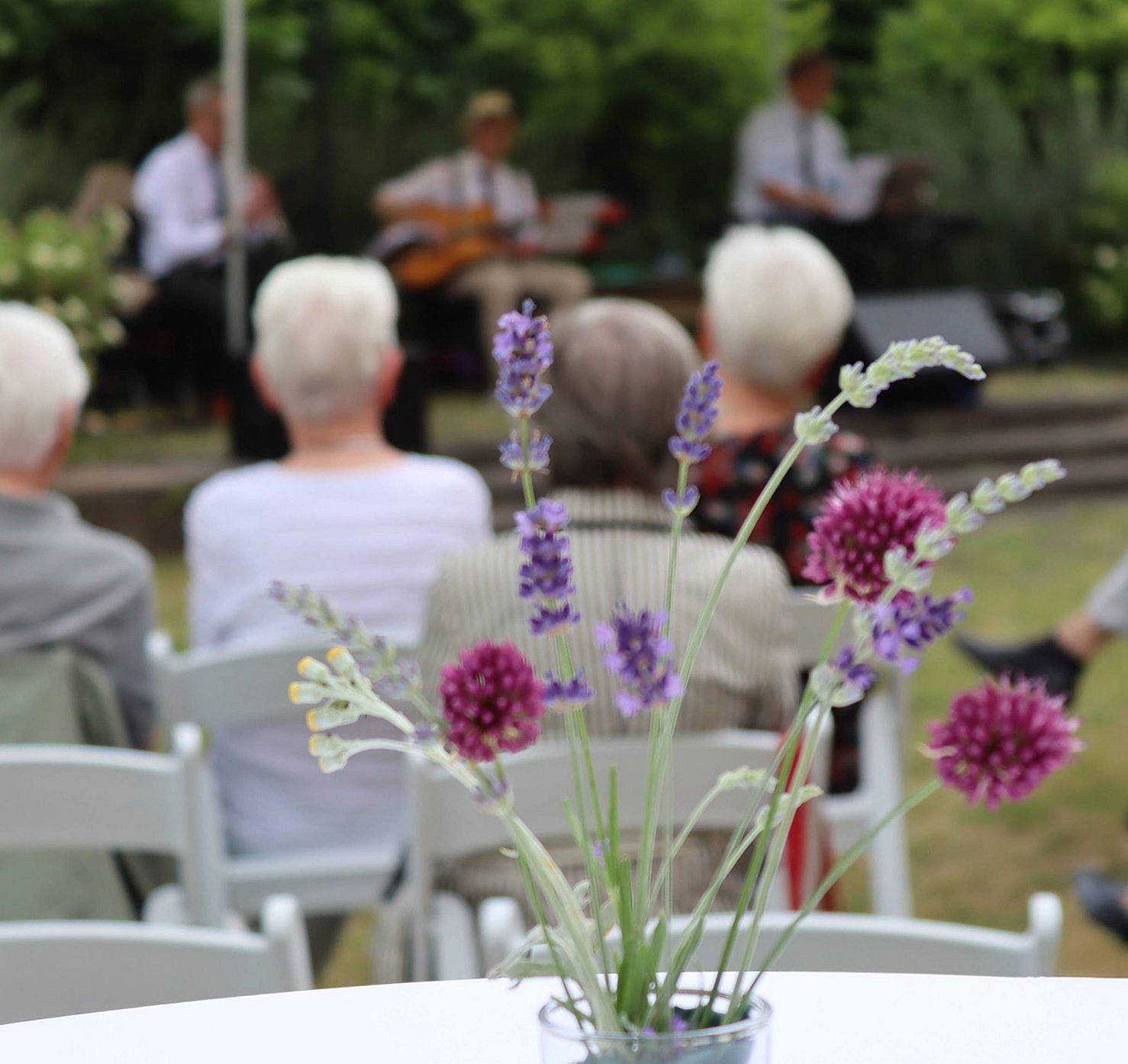 Sommerfest 2025 ©Stiftung Kleist-Museum Ein Blumenarrangement mit lila- und pinkfarbenen Blumen vor einem Konzert im Freien in entspannter Atmosphäre